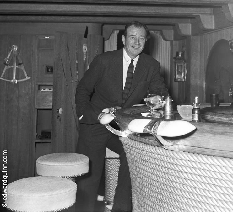 John Wayne at the bar of Onassis' yacht Christina. Monaco 1955.