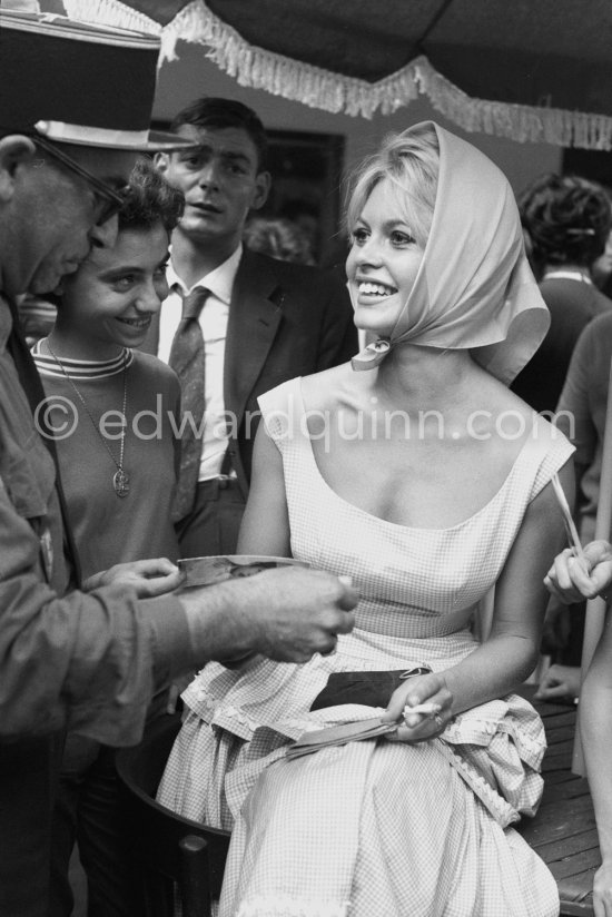 Brigitte Bardot signing a set card for a gendarme. Saint-Tropez 1958. - Photo by Edward Quinn