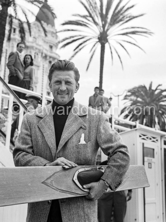 Kirk Douglas with his surfboard in front of the Carlton Hotel. Cannes Film Festival 1953. - Photo by Edward Quinn