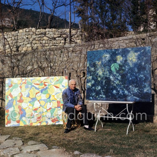 Max Ernst in the garden of his home with "La fête à Seillans") and on the table the first version of "Der letzte Wald" ("La dernière forêt"), 1960-1969. Seillans 1966. - Photo by Edward Quinn