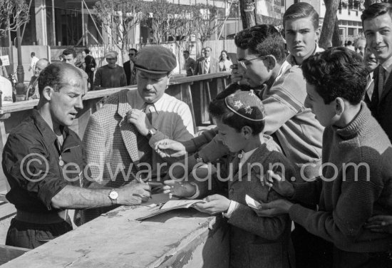 Stirling Moss signing autographs. With him is Colin Chapman. Monaco Grand Prix 1957. - Photo by Edward Quinn