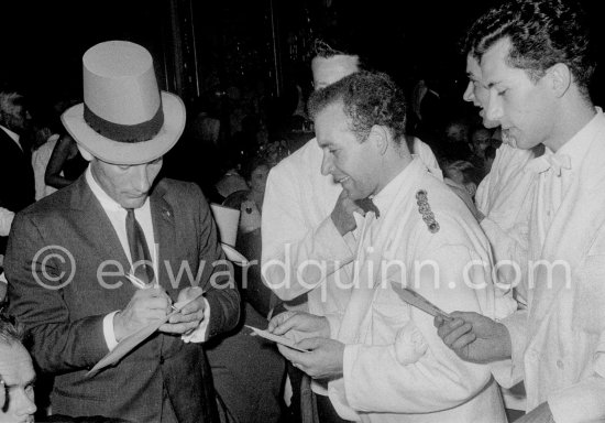 Stirling Moss, winner of the Grand Prix, gsigning autographs for the waiters. Gala of Monaco Grand Prix 1960. - Photo by Edward Quinn