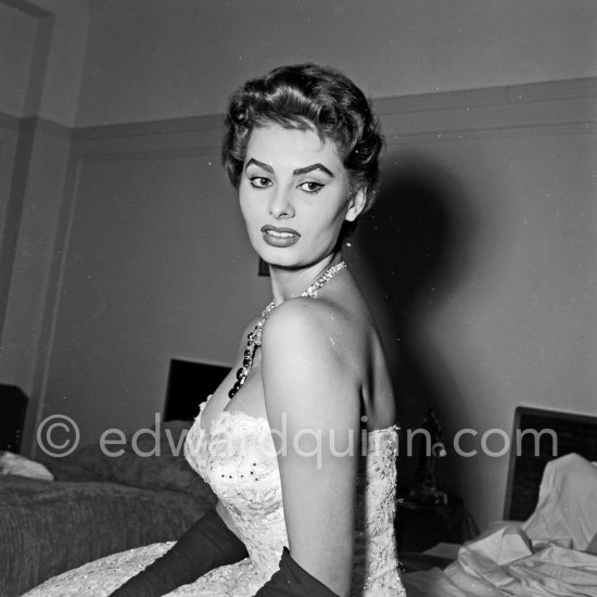 Sohia Loren in her Carlton Hotel room during the Cannes Film Festival wearing an evening gown designed by Emilio Schuberth, 27 April 1955. - Photo by Edward Quinn