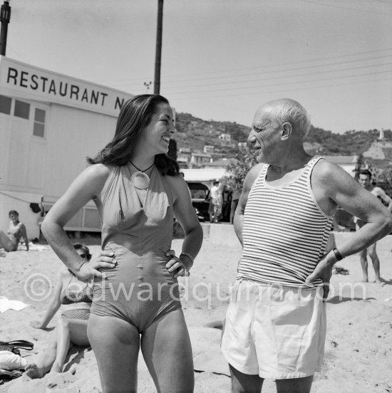 Pablo Picasso and Françoise Gilot (with pendant by Pablo Picasso) in front of restaurant Nounou. At the beach of Golfe-Juan 1954. - Photo by Edward Quinn