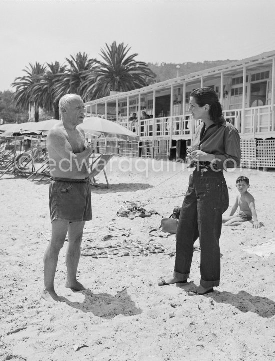 Françoise Gilot and Pablo Picasso, Claude Picasso in the background at the beach. Restaurant Nounou. Golfe-Juan 1954. - Photo by Edward Quinn