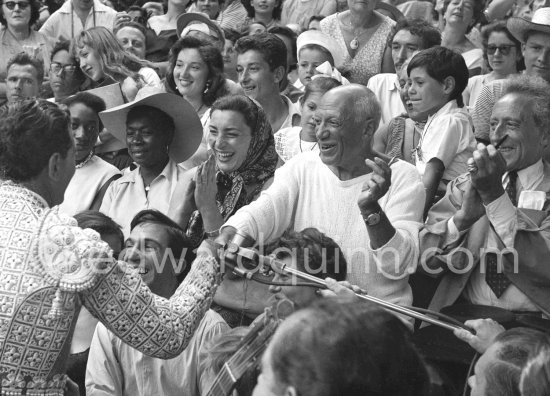 On the grandstand of a bullfight put on in Pablo Picasso\'s honor. From left: Bandrillero andaluz Francisco Reina, "El Minuni", Javier Vilató, Jacqueline, Pablo Picasso, Jean Cocteau. Behind them Paloma Picasso, Maya Picasso and Claude Picasso. Vallauris 1955. - Photo by Edward Quinn