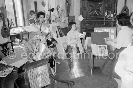 Paloma Picasso pulls a surprise cracker with Catherine Hutin. The Dominguin children and Inès Sassier, Pablo Picasso\'s housekeeper look on. The book open on the armchair shows a portrait of Paloma Picasso. Pablo Picasso, La Californie, Cannes 1959. - Photo by Edward Quinn