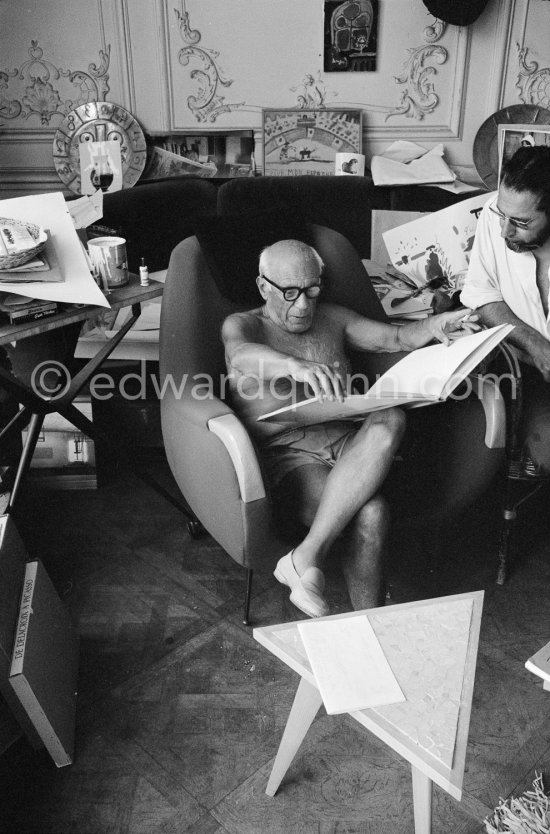 Pablo Picasso with Georges Tabaraud (editor of "Le Patriote", a french communist daily Newspaper). Pablo Picasso reading a book on himself. Ripolin can in the background on a table by Joseph-Marius Tiola. La Californie, Cannes 1961. - Photo by Edward Quinn