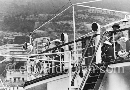 Grace Kelly and Prince Rainier on his yacht Deo Juvante II. She came ashore from the liner S.S. Constitution, which brought her to Monaco for her marriage. Monaco 1956.She wore a matching navy blue silk dress and coat by Ben Zuckerman of New York with a fashonable but troublesome wide-brimmed hat. - Photo by Edward Quinn
