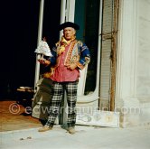 Pablo Picasso in a whimsical costume. Among other things, he has on a bullfighter’s jacket, given to him by his friend, the famous matador Dominguin. On the floor a mosaic Hjalmar Boyesen executed after a Pablo Picasso design. In front of the garden gate at La Californie. Cannes 1956. - Photo by Edward Quinn