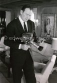 John Wayne checking out a Pathé film camera on board Onassis\' yacht Christina, Monaco harbor 1955.