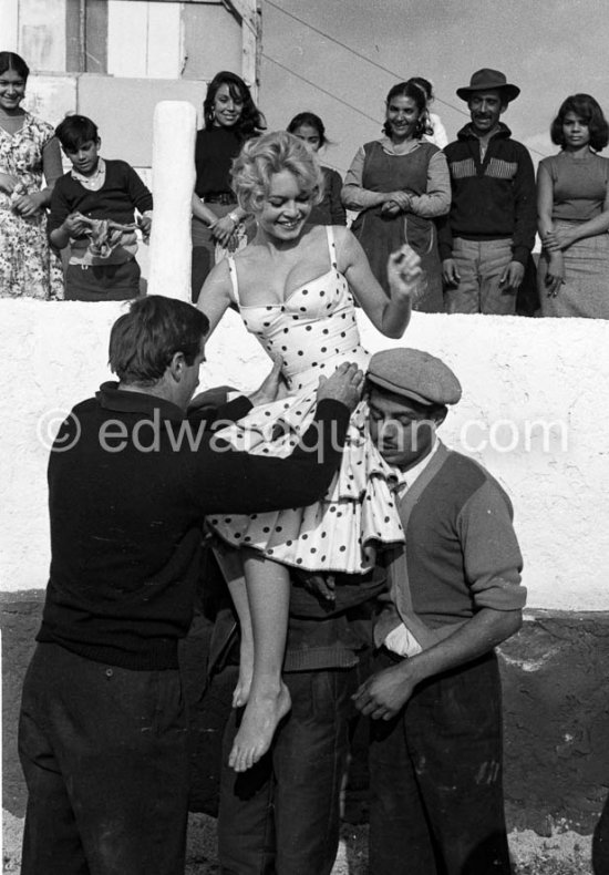 Brigitte Bardot during the filming of the last scenes of „Les Bijoutiers du clair de lune“ (“The Night Heaven Fell”), on the grounds of the Victorine Film Studios in Nice. Directing the film is Brigitte’s ex-husband Vadim. Brigitte is carried by two gipsies. The scene is supposed to represent Brigitte being carried victoriously out of the bull ring, after having given battle to a bull. All people in the back, young and old, are gipsies. Nice 1958. - Photo by Edward Quinn