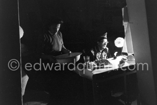 Watched by his wife Gala, Salvador Dalí works on his experiments with the sea urchin holding a swan feather and moving backwards and forewards thus marking the blackened paper. These experiments he is carrying out at his studio in his Spanish home at Portlligat, Cadaqués, on the Costa Brava 1957. - Photo by Edward Quinn