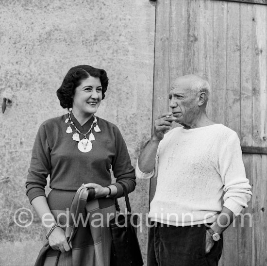 Pablo Picasso with Madame Paule de Lazerme (she had an affair with Pablo Picasso for some months) who wears a necklace designed by Pablo Picasso, made with the help of the Vallauris dentist Dr. Chatagnier. In front of the studio Le Fournas, Vallauris 1953. - Photo by Edward Quinn