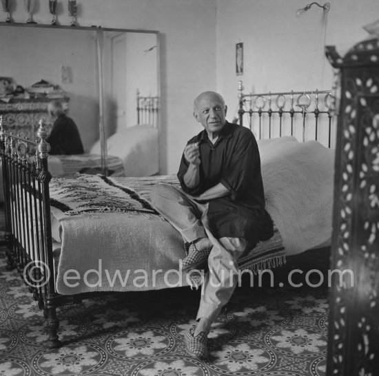 Picasso completely at ease, with baggy, unpressed trousers, a very loose-fitting shirt and carpet slippers, in his bedroom at La Galloise, Vallauris 1954. - Photo by Edward Quinn