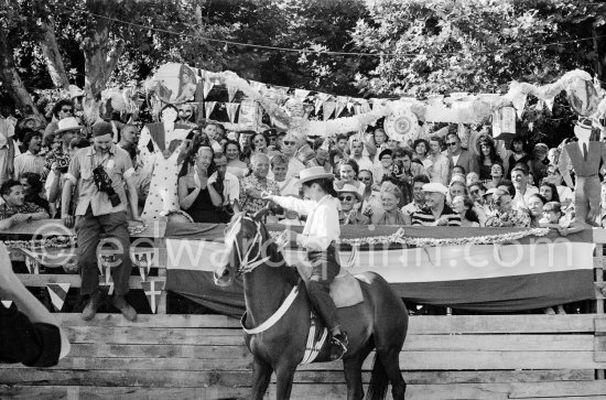 Françoise Gilot, led the toreadors into the bull ring and is here seen shaking hands with Pablo Picasso. On the grandstand singer Yolanda on Pablo Picasso\'s right, Hélène Parmelin, Edouard Pignon, far right Paloma Picasso with her nanny. Corrida Vallauris 1954. - Photo by Edward Quinn