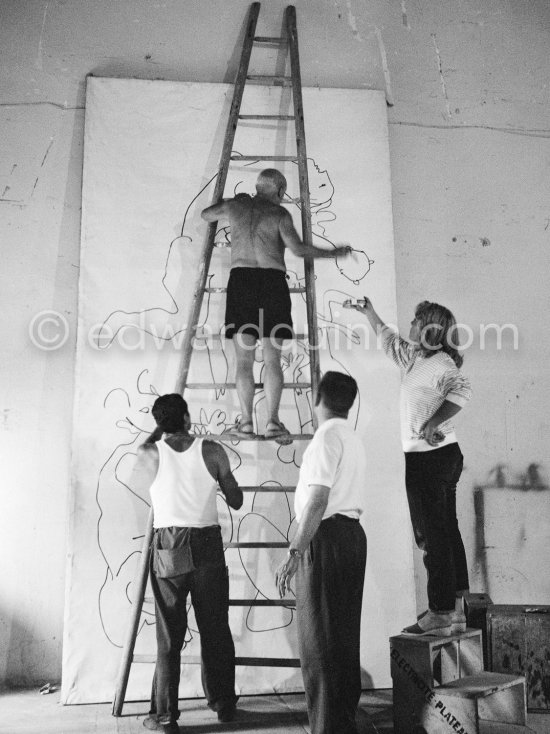 Pablo Picasso working on a bucolic pastoral scene on drawing paper which was to serve as background for the film "Le mystère Picasso". Maya Picasso on the right. Nice, Studios de la Victorine 1955. - Photo by Edward Quinn