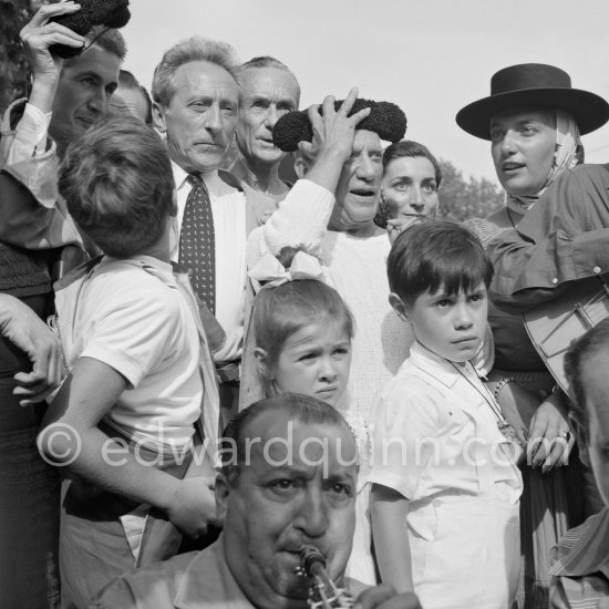 At Pablo Picasso\'s arrival on the village square where the corrida is to be held the band blares out some of his favourite Spanish melodies. From left Jean Cocteau, Jacques-Henri Lartigue, Pablo Picasso, Jacqueline, Maya Picasso and in front Paloma Picasso and Claude Picasso. Vallauris 1955. - Photo by Edward Quinn