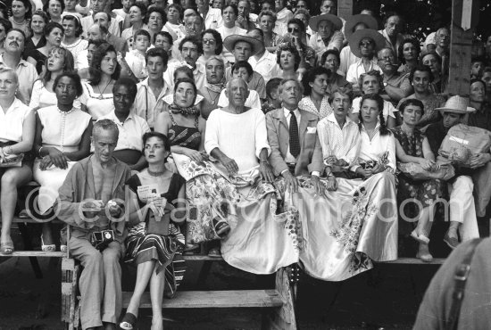 On the grandstand of a bullfight put on in Pablo Picasso\'s honor. On the left of Pablo Picasso Jacqueline, on the right Jean Cocteau, Inès Sassier, Pablo Picasso\'s housekeeper and Francine Weisweiller and her daughter Carole, behind Pablo Picasso his children Paloma Picasso, Maya Picasso and Claude Picasso, in front on the left photographer Jacques-Henri Lartigue, loading a film in his Rolleiflex, and his wife Florette. Vallauris 1955. - Photo by Edward Quinn