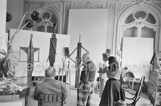 Pablo Picasso showing Suzanne and George Ramié wood sculptures "The Bathers (Les Baigneuses)". On the right Jacqueline. La Californie, Cannes 1957. - Photo by Edward Quinn