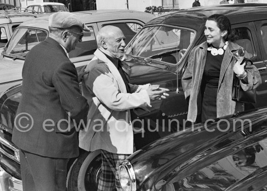 Jaime Sabartés, Jacqueline and Pablo Picasso on Mayday. Jacqueline is holding some sprigs of "muguet", the traditional flower of the day. She\'s wearing a ceramic necklace made for her by Pablo Picasso. La Croisette, Cannes 1957. - Photo by Edward Quinn