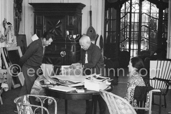 Pablo Picasso correcting "Faunes et chèvres". With Jacqueline (wearing a blouse with Pablo Picasso motifs) and probably chauffeur Jeannot. La Californie, Cannes 1959. - Photo by Edward Quinn