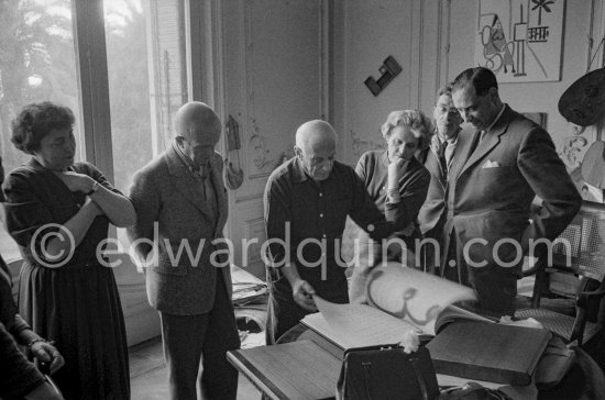 Pablo Picasso shows the first copy of a deluxe edition of a book of poems by Pierre Reverdy, for which he has made the illustrations. Gathered around him as he comments on the book are Lucie Weill, the writer Michel Leiris, his wife Louise Leiris, owner with Daniel-Henry Kahnweiler of the Leiris Gallery Paris, a Paris publisher and André Weill, publisher of some deluxe editions of Pablo Picasso\'s work. La Californie, Cannes 1959. - Photo by Edward Quinn