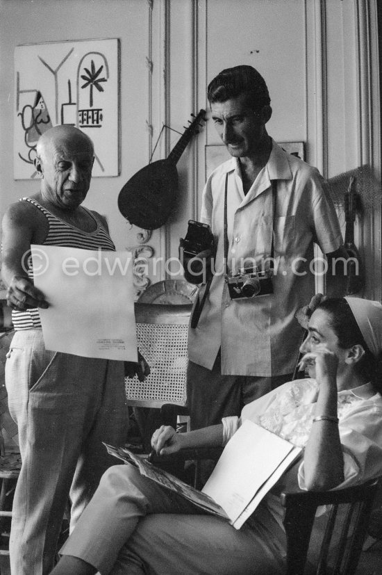 Pablo Picasso, Jacqueline and Edward Quinn discuss a choice of photographs for the book "Pablo Picasso at Work". Quinn with his Leica M3 and Rolleiflex 3.5B. La Californie, Cannes 8.9.1960. Photographer unknown. - Photo by Edward Quinn