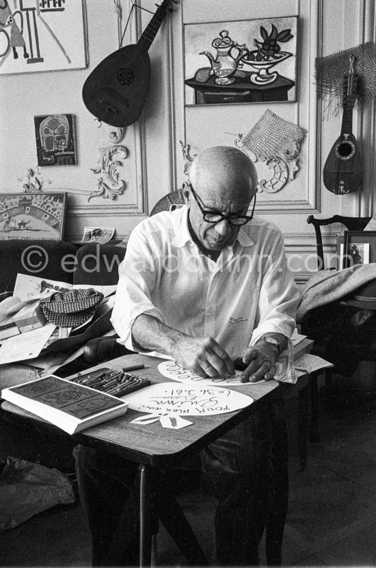 Pablo Picasso working on "Oeuf de pâques" with Caran d\'ache wax oil pastels. On the left invitation cards for the opening of an exhibition at La Galerie Madoura, 5 april 1961. La Californie, Cannes 1961. - Photo by Edward Quinn