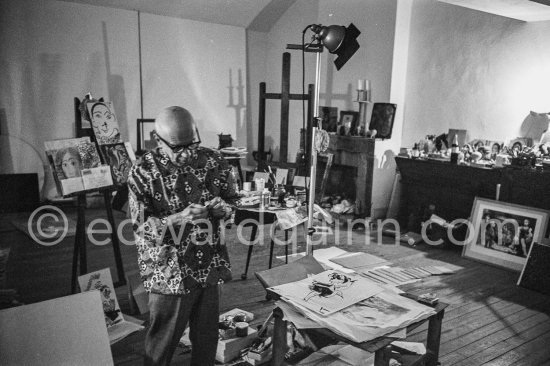 Pablo Picasso checks a small lucky dollar coin on which he engraved his ...