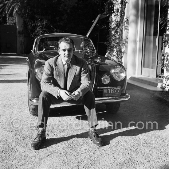 Car enthusiast Prince Rainier of Monaco at his Villa Iberia. He competed under the pseudonym of Louis Carladès at the Tour de France de l\'automobile and crashed into a tree. Saint-Jean-Cap-Ferrat 1954. Car: Lancia Aurelia B20 Gran Turismo 2500 - Photo by Edward Quinn