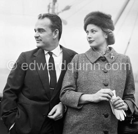 Rainier, Prince of Monaco and Princess Grace. On board the liner "Constitution", arriving from the U.S. after a six week trip to the United States. Monaco 1956. (Grace Kelly). She wears a tailored suit with a gently flared jacket and the Cartier brooch in the shapeof a poodle that was one of her favorite pieces of jewelry. - Photo by Edward Quinn